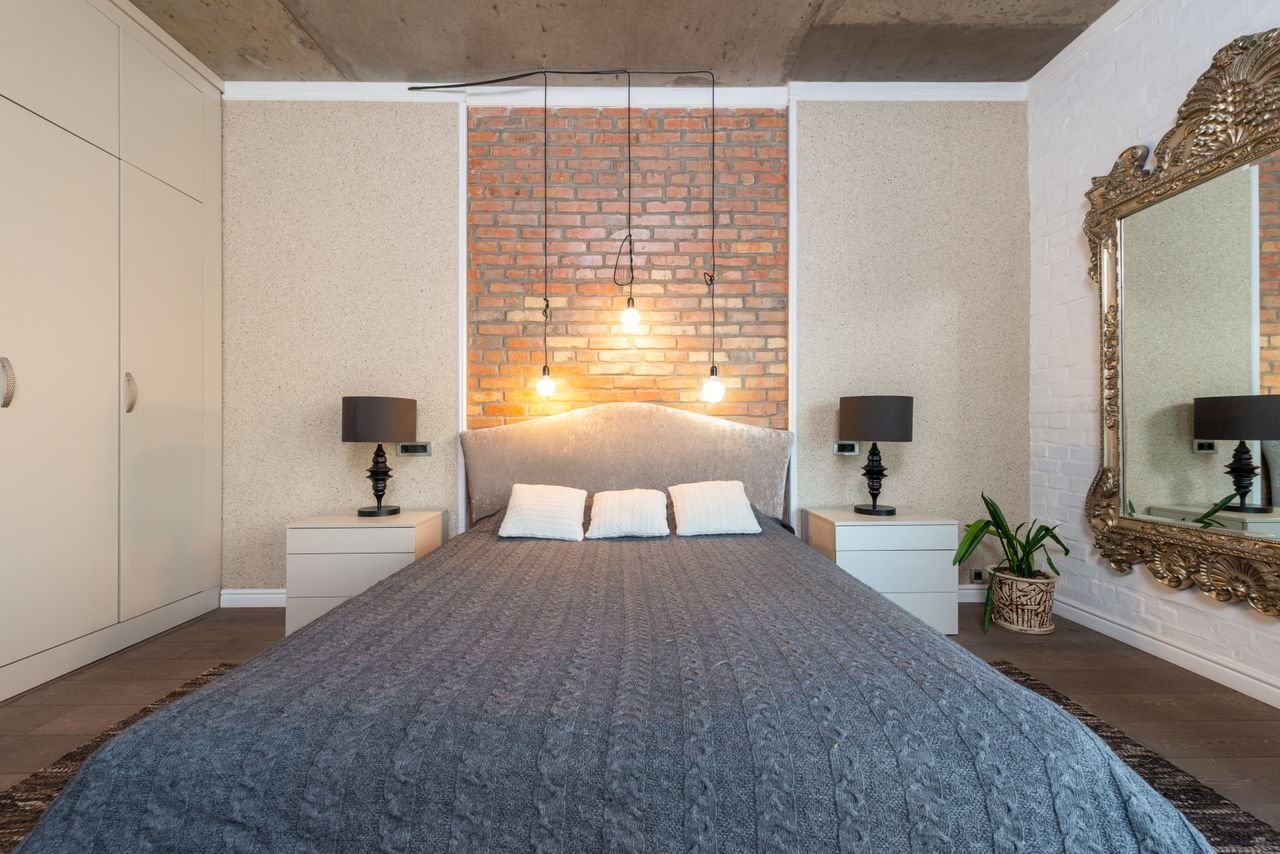 Cozy bedroom with exposed brick wall, bed, and bedside lamps